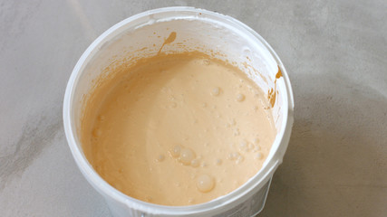 Plastic bucket with beige paint. Home renovation concept.