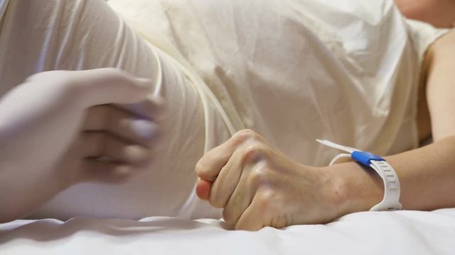 Pregnant woman in hospital. Woman in the last months of pregnancy is experiencing severe pain, doctor takes the patient by the hand and tries to reassure. Close-up footage