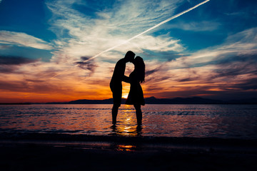 Silhouette couple kissing standing in sea