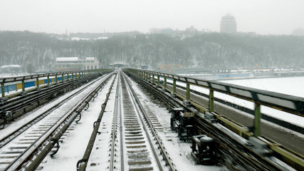 Train moves through the bridge at snow stormy day time. Train moves on bridge in winter season. Route of tube train.