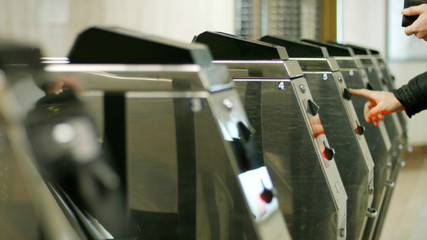 Metal turniquets in the underground. Woman entering the a underground station.