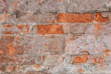 abstract background of an old brick wall with peeling plaster and the remains of pink paint close up