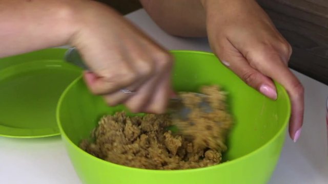 A woman vigorously mixes a cookie crumb with condensed milk. Cooking basics for cake pops.