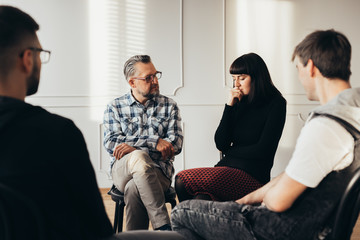 School counselor talking to depressed teenager during group therapy