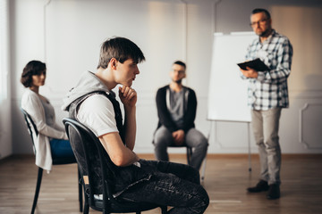 Obraz premium Young man thinking about an answear during group coaching session