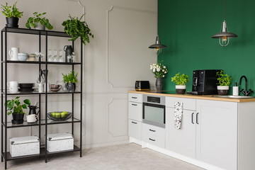Fashionable kitchen interior with grey cabinets and industrial metal shelf with plates and glasses