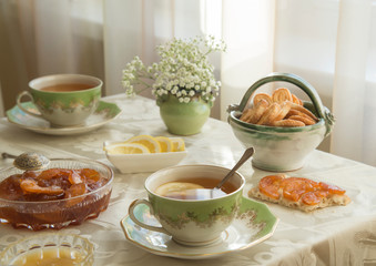 Delicious fresh breakfast for two. Tea with lemon, apple jam and biscuits