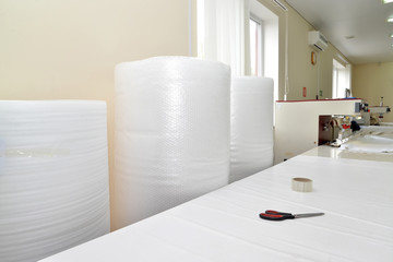 Rolls of an air and bubble film stand in the shop on production of stretch ceilings