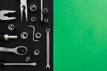 Flat Lay Composition With Different Construction Tools on Black and Green Background. Top View of Checklist and Working Tools, Wrench, Screwdriver, Plier.