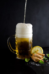 in a glass of beer beer and shrimps the scattered salt and a lemon a rcherny background pour, selective focus