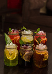 Six glasses of homemade different decorated summer drinks of lemonades on a wooden table Copy space