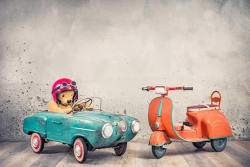 Papier Peint photo Scooter Retro Teddy Bear toy racer dans un vieux chapeau de casque avec des lunettes conduisant une voiture à pédales bleu menthe rouillée antique des années 60 et fond de mur de béton avant tricycle scooter pour enfants orange. Style vintage filtré
