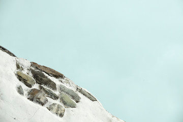 Part of a stone wall with the blue sky on the background. Stone wall details.