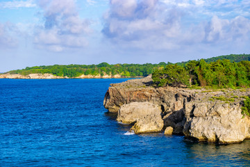 Cliff side/cliffside coastline view on tropical Caribbean island ocean. Scenic mountainous rock formations from sea erosions along coast of Portland Jamaica. Sunny summer day on coastal countryside.