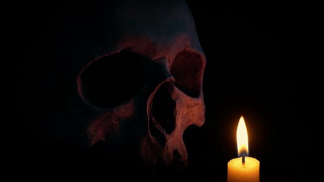 Candle Burning Next To Old Skull