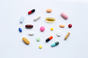 Colorful tablets with capsules and pills on white.