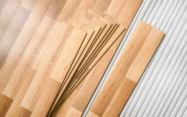 Tiles of laminated floor with wooden effect laying on white base foam, ready to be installed