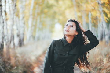 Dreamy beautiful girl with long natural black hair on bokeh background of autumn yellow leaves....