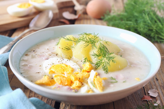 Traditional polish soup Zurek. Sour soup with sausage,  potatoes and eggs in ceramic bowl
