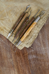 Close-up of various sculpting tools for clay modelling on dirty napkin placed on wooden table