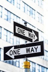 Close-up view of 'one way' road sign with blurred building in the background. Manhattan, New York City, United States of America.