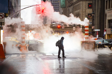 A black male is crossing the 42nd street in Manhattan while steam coming out from from the...