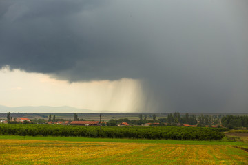 Thunderhead covers the Balkans. Downpour is approaching agricultural land. Bulgarian villages...