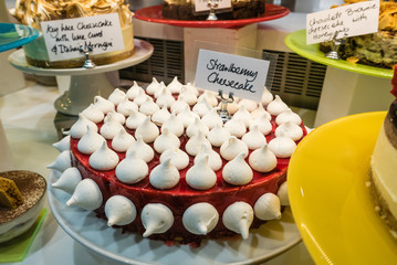 Strawberry cheesecake dessert with mini meringues on display in a restaurant
