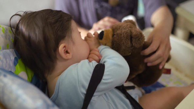 Mother playing with bear anb her baby son in the child seat - Asian mixed ethnicity child Boy wearing blue body shirt with smiling bear cartoon Pregnant