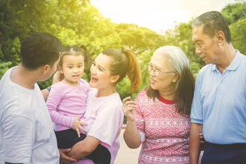 Cheerful multi generation family chatting in park