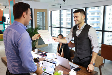 two caucasian businessmen holding success business certificate with happy and smiling face in modern office