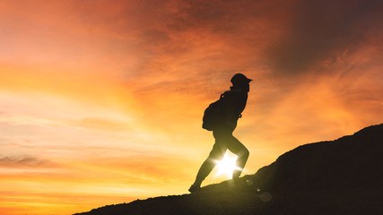 Female hiker climbing a hill at sunset time
