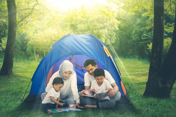 Muslim family reading books in the camping tent