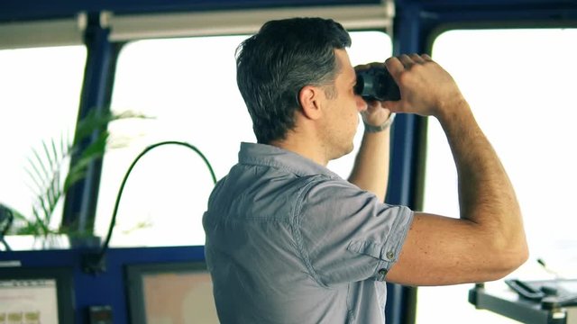 Navigational officer lookout on navigation watch looking through binoculars. Marine industry. COLREG collision regulations