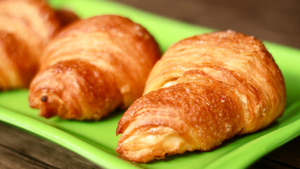 Croissants on green plate. Wood background. 