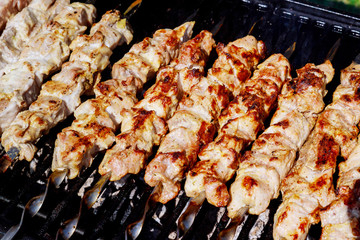 Close up of pork kebabs cooking on a barbecue.