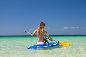 Sexy tanned girl in white bikini sunbathing on board. Beautiful model sunbathes and rests on sea. Concept vacation, travel
