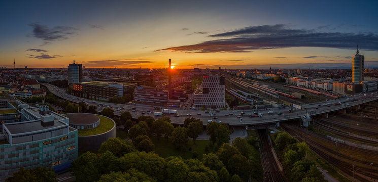 Munich from above at a beautiful sunrise. The red sun next to the famous Frauenkirche by the view from the Donnersberger Br cke with traffic made by drone.