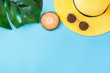 summer blue banner with yellow hat ,sunglasses and monstera leaf on blue background top view.