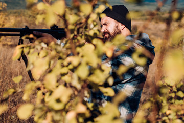 Naklejka premium Autumn hunting season. Hunter with shotgun gun on hunt. Hunter in the fall hunting season. Hunter aiming rifle in forest. Track down.