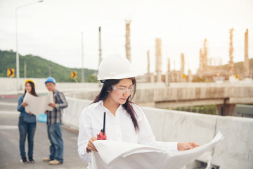 Smart woman engineer holding white hard hat on hand and look at refinery industry plant at industry factory center area. Engineering Concept