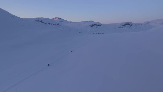 A half-track car with skies in the sunset. You can see the Jotunheimen in Norway in the background. 
Filmed in 4k from a drone.