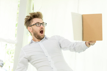 Fototapeta premium Caucasian man holding text book study hard surprise in content. education concept