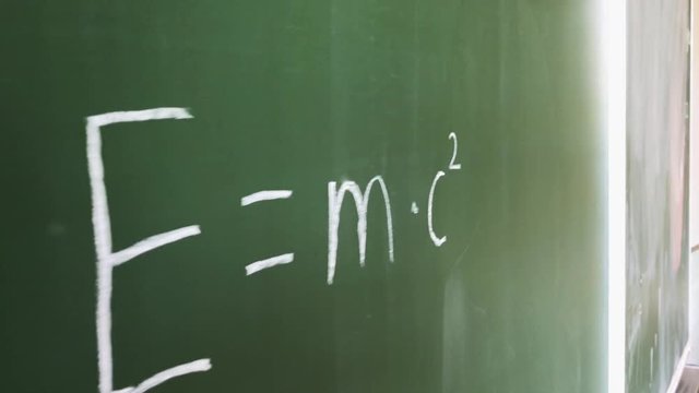 Albert Einstein's theory of relativity formula written with chalk on a board.