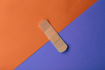 Adhesive bandage or Sticking plaster on a two colored paper background.