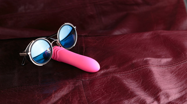 Pink vibrator in sunglass on a red leather background. Mr Cooldick.