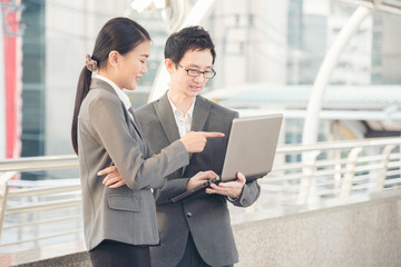 Young beautiful working woman discuss on site service with colleague businessman holding laptop. Business technology concept