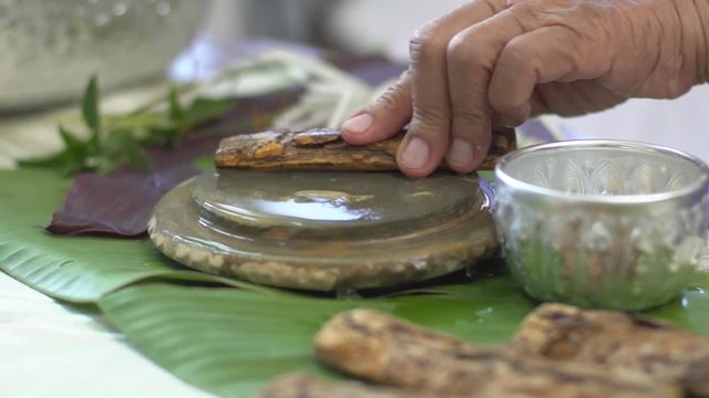 Thanaka herb bark scrubbing on kyauk pyin stone slab . thanaka is a popular cosmetic paste made from ground bark in Myanmar