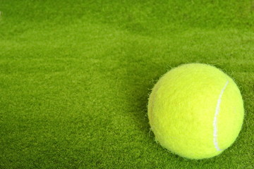 yellow tennis ball on the green grass lawn court in corner