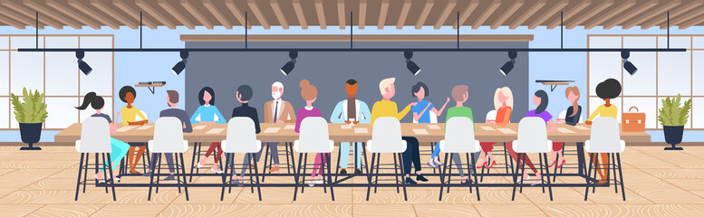 businesspeople group brainstorming sitting at round table during conference meeting mix race coworkers discussing new project in co-working open space interior flat horizontal